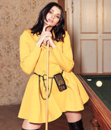 Frau in gelbem Kleid, die unsere schwarze Ledertasche für das iPhone 13 in einer anderen Variante präsentiert.